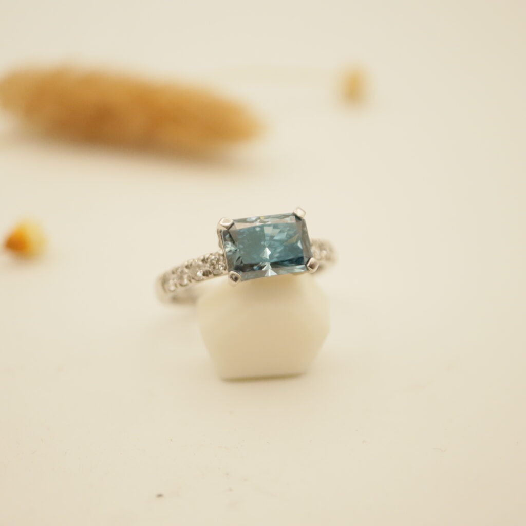 bague de fiançailles en or blanc avec un diamant rectugiulaire pan coupé de couleur bleu création Astrid.C