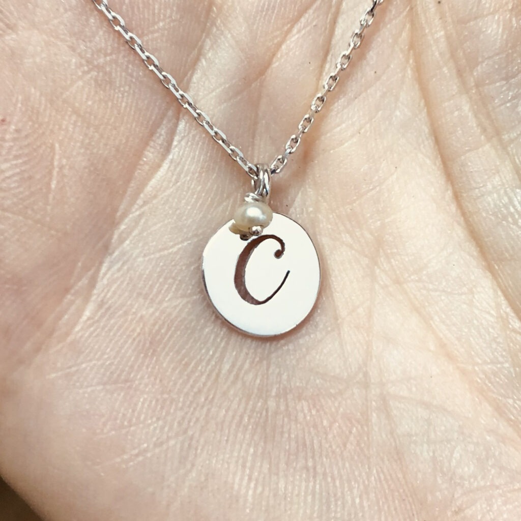 collier avec une médaille en or blanc et sa lettre C en repercé accompagnée d'une perle de culture